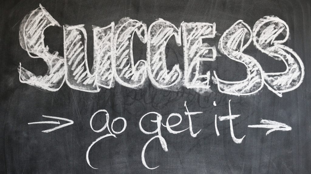 A chalkboard with the word "SUCCESS" written in large letters and "go get it" written below, accompanied by arrows pointing outward from "SUCCESS.